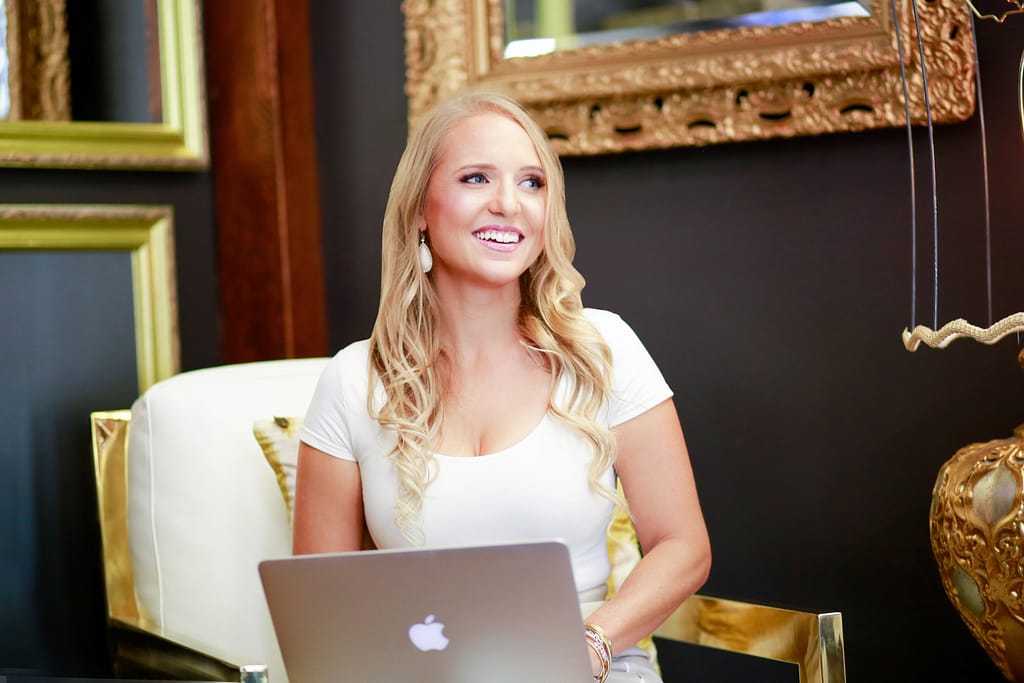 blonde girl smiling holding a laptop
