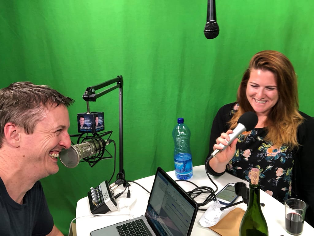 man and woman laughing while recording a podcast