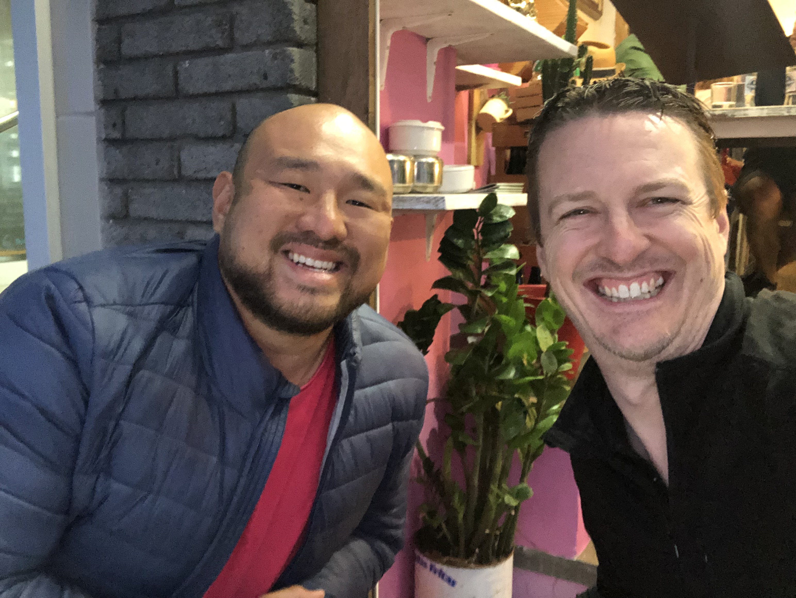 two guys smiling with a plant